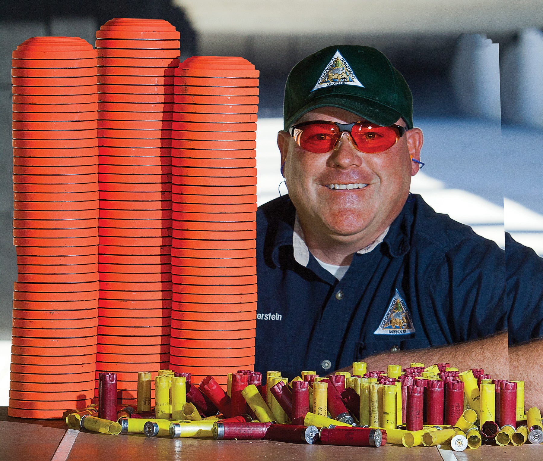 Man posing with a big stack of clay pigeons and shotgun shells