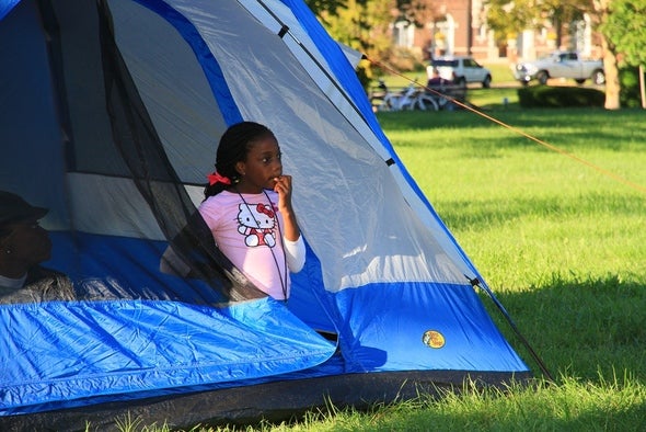 A child sitting in a tent in Forest Park.