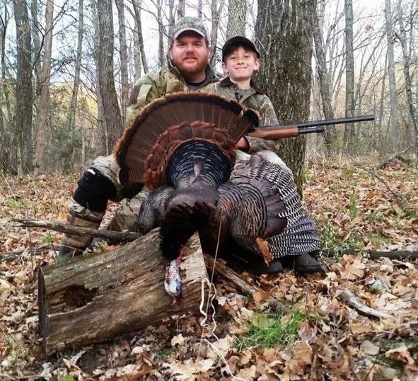 A young hunter and his mentor proudly show off a turkey he harvested. 