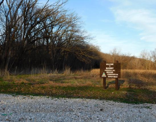 McKinny Conservation Area welcome sign near parking area, with view of landscape beyond