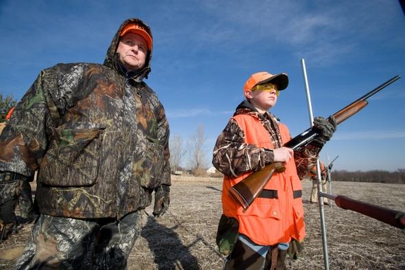 An adult man and young boy learning gun and hunter safety.
