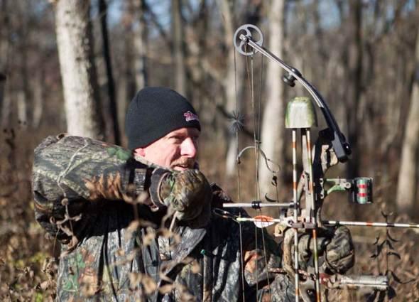 Bowhunter in camoflage pulling back on a bow
