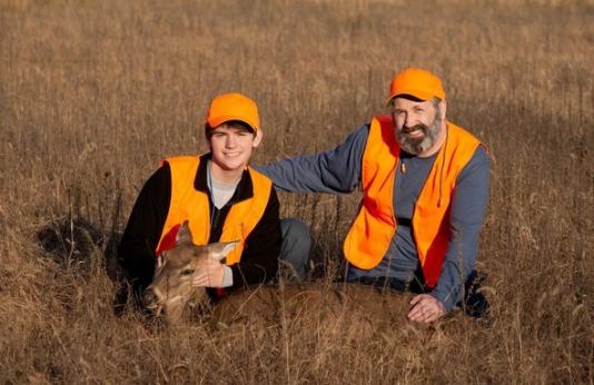 Youth hunter with harvested deer and mentor