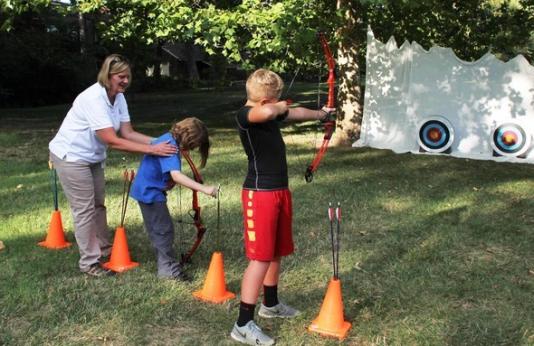 MDC staff member teaches two boys archery
