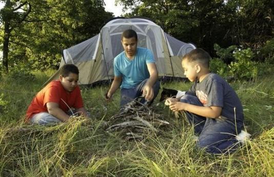 Kids make campfire near their tent