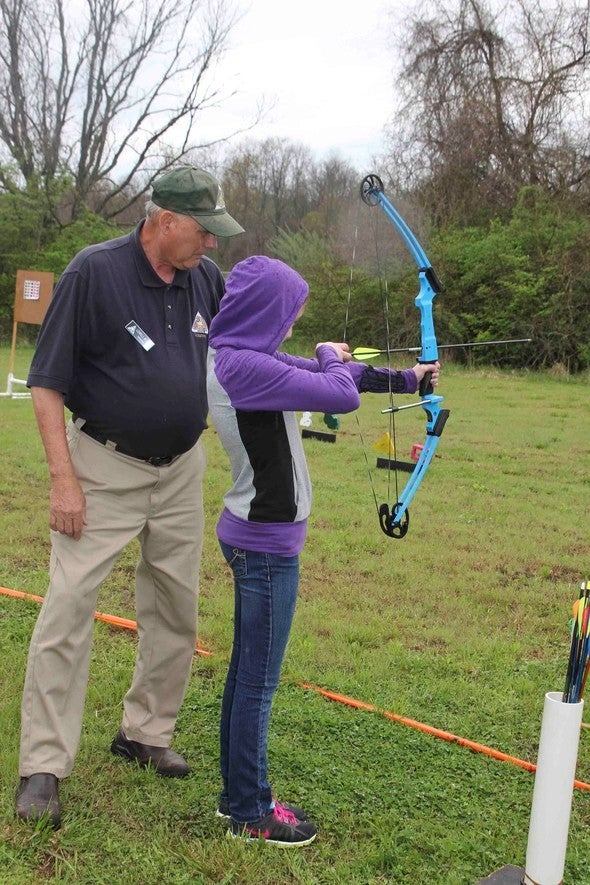 man teaching girl archery