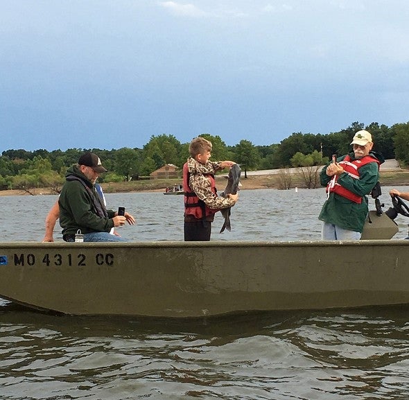 Young angler holds catfish on john boat