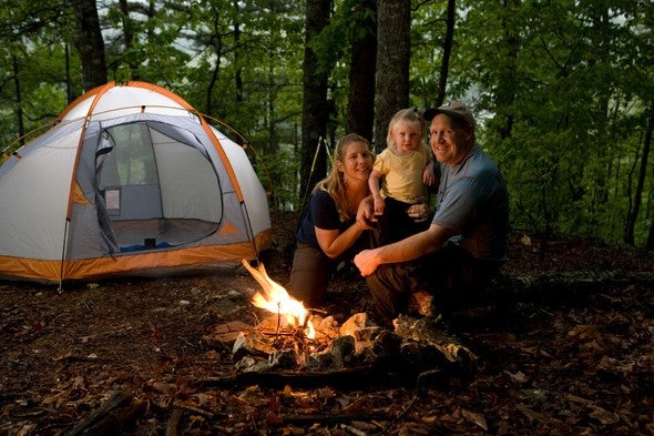 Young couple and toddler at campsite with fire