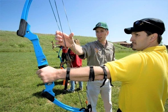 MDC staff person teaching archery to man