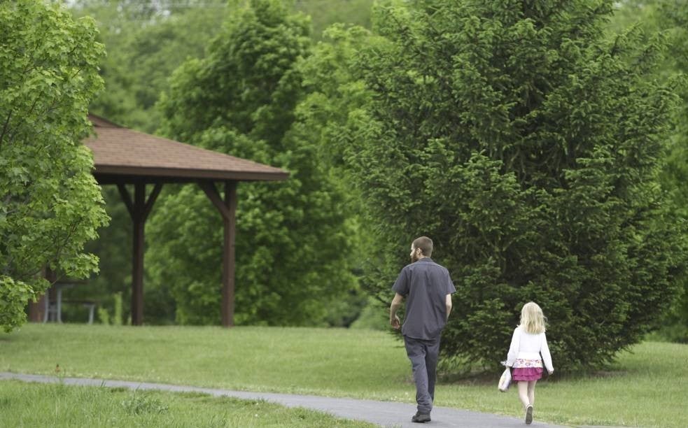 Father and daughter walk in city park