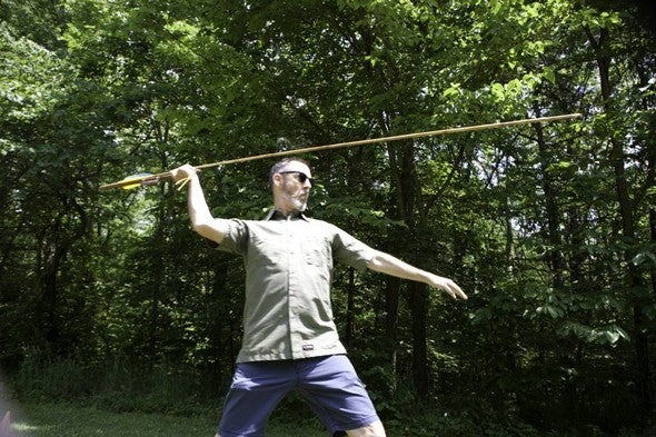 Man gears up to throw atlatl.
