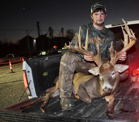 Hunter with harvested deer in bed of truck