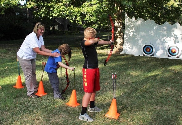 MDC staff member teaches two boys archery