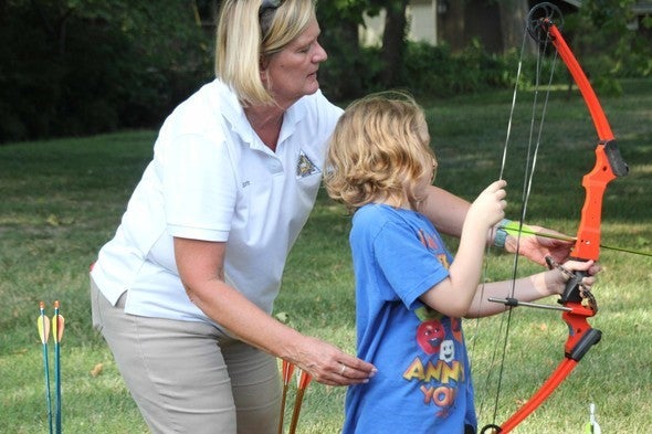 MDC staff member teaches child archery