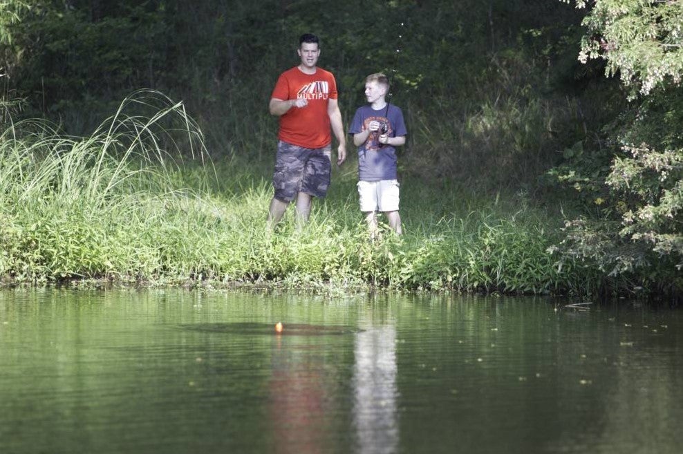 Father and son fish at pond