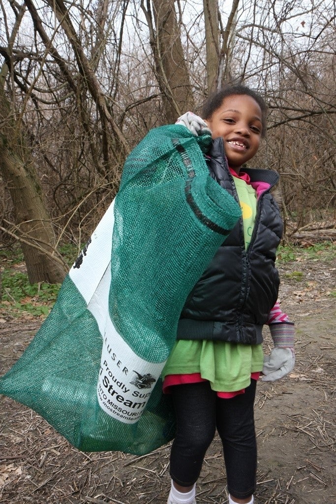 Little girl holds sack of trash 