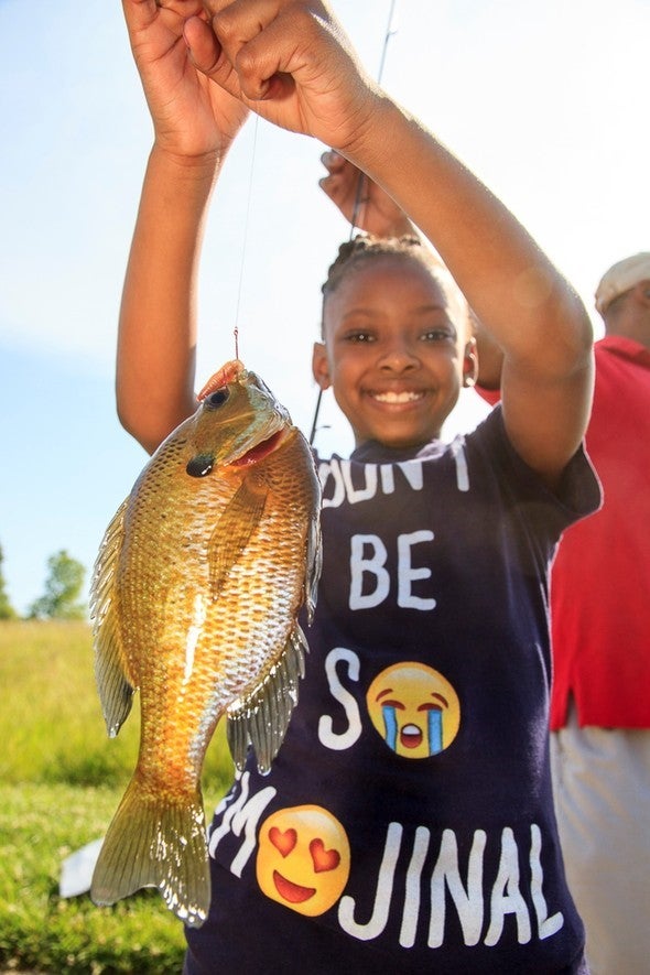 Girl holds bluegill on fishing line
