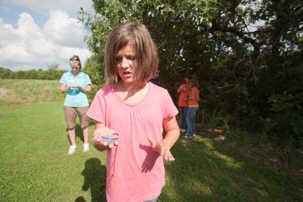 Young girl orienteering outside with compass