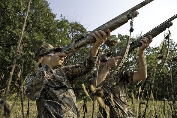 Two dove hunters aim shotguns to the sky