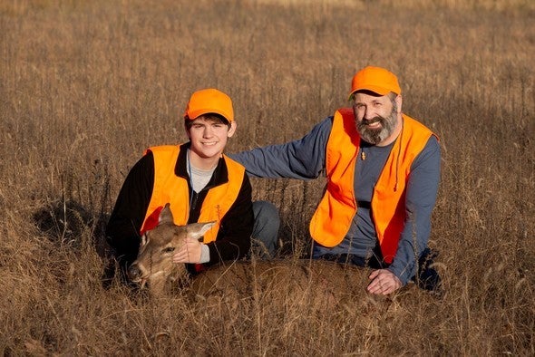 Young hunter and mentor pose with harvested deer