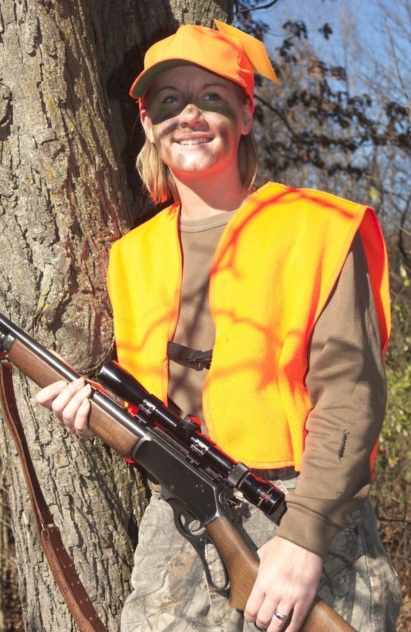 Woman deer hunter in woods with rifle
