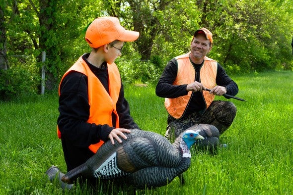 Boy and father turkey hunting with decoys