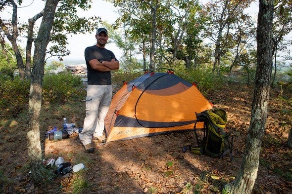 David Stonner smiles next to his campsite