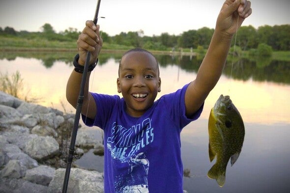 Boy smiles and shows a bluegill to the camera