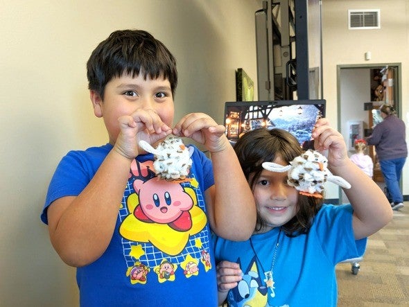 A young boy and girl show off their nature holiday ornaments