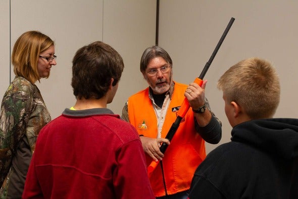 MDC staff member demonstrates firearm safety to two teenage boys and a woman.