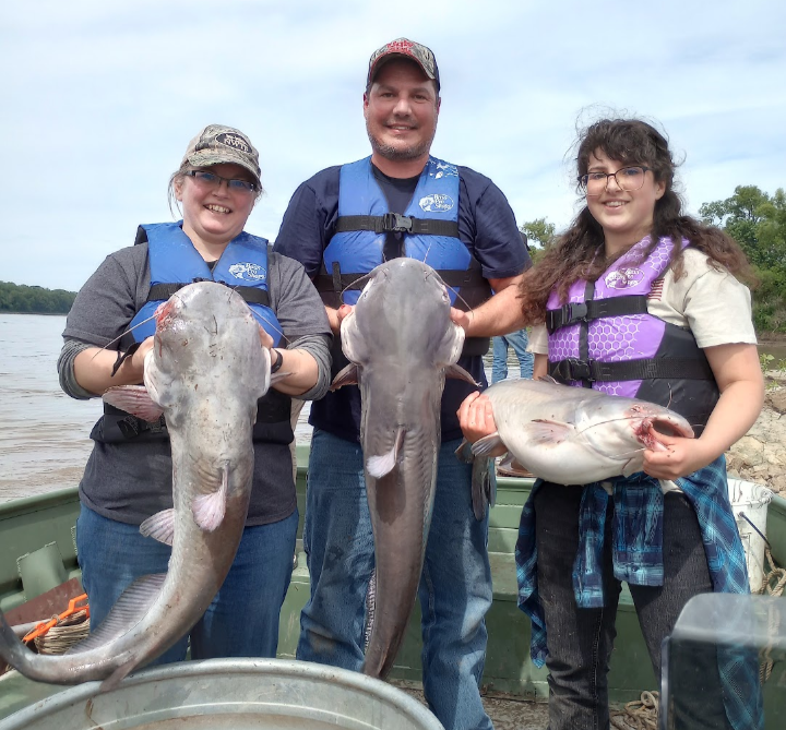 three people holding three large catfish