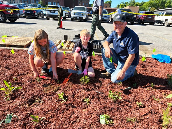 Brad McKee with two students planting flowers