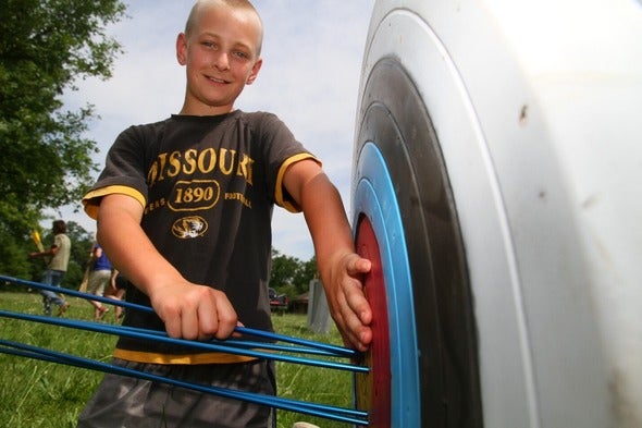 boy pulling arrow from archery target