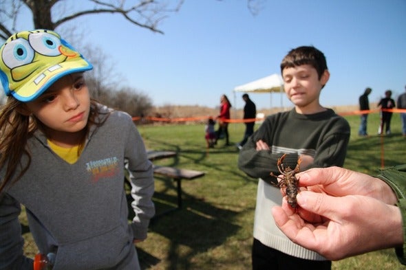 person holding crayfish as girl looks at it