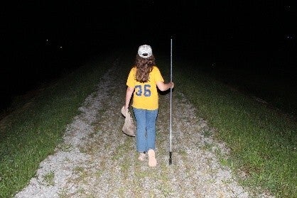 person with frog gigging pole and net