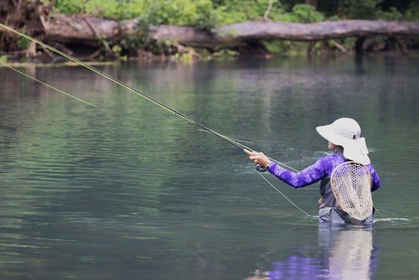 woman trout fishing in stream