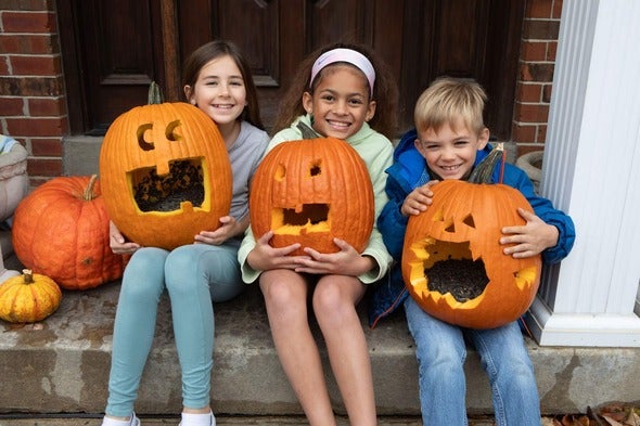 Children pose with carved pumpkins for Halloween. 