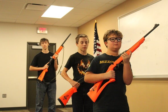 Three young boys stand holding simulation rifles for hunter education in Missouri