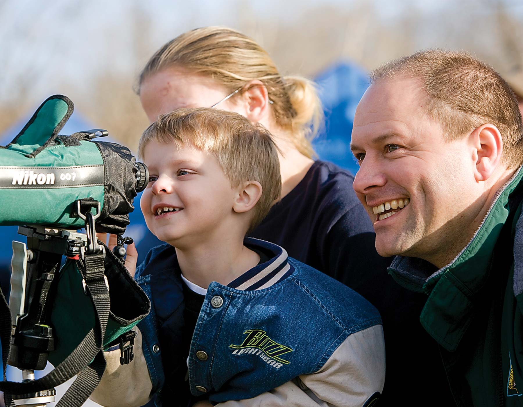 father and son watching animals through a telephoto lens