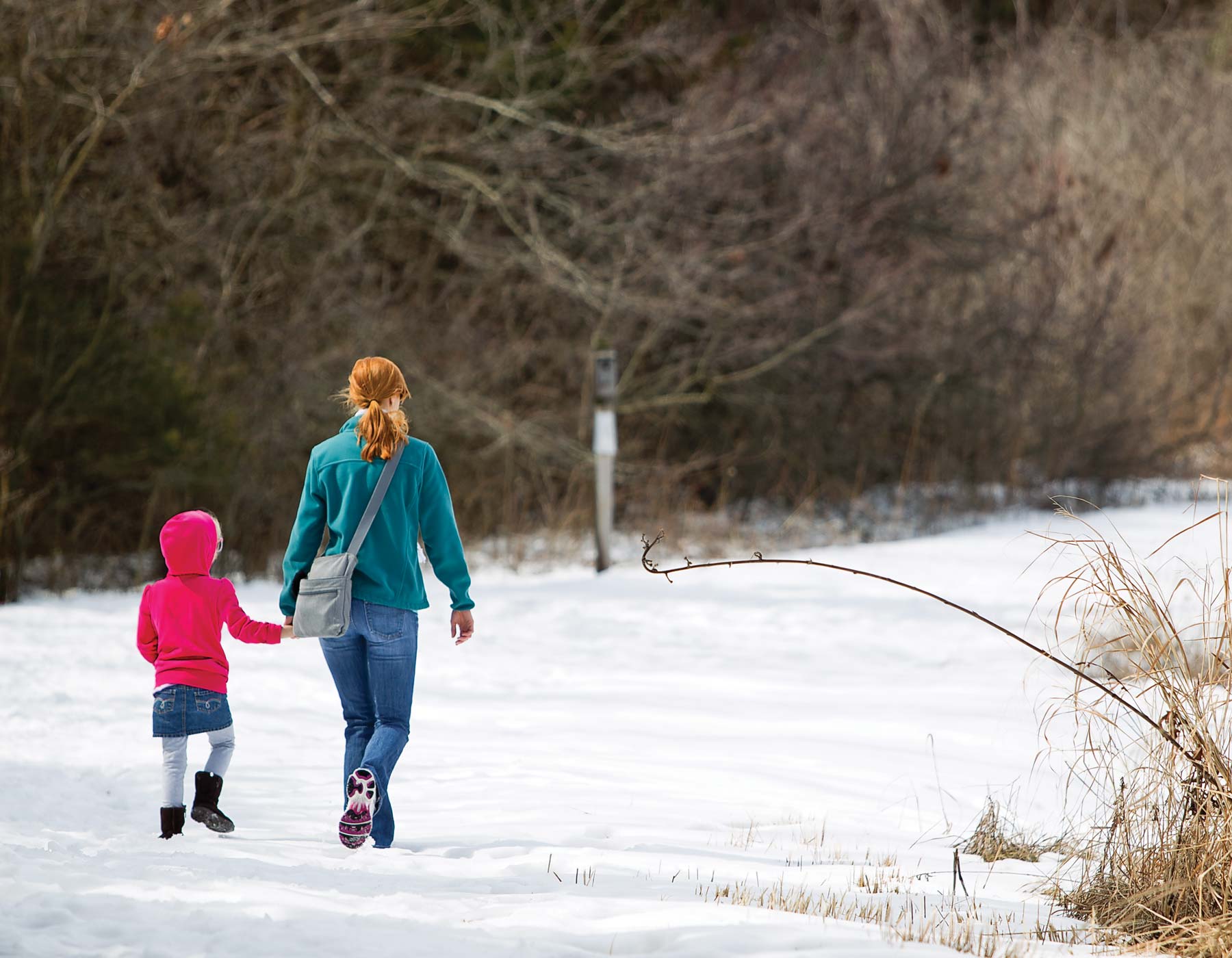 A woman and child take a winter walk on a snowy path