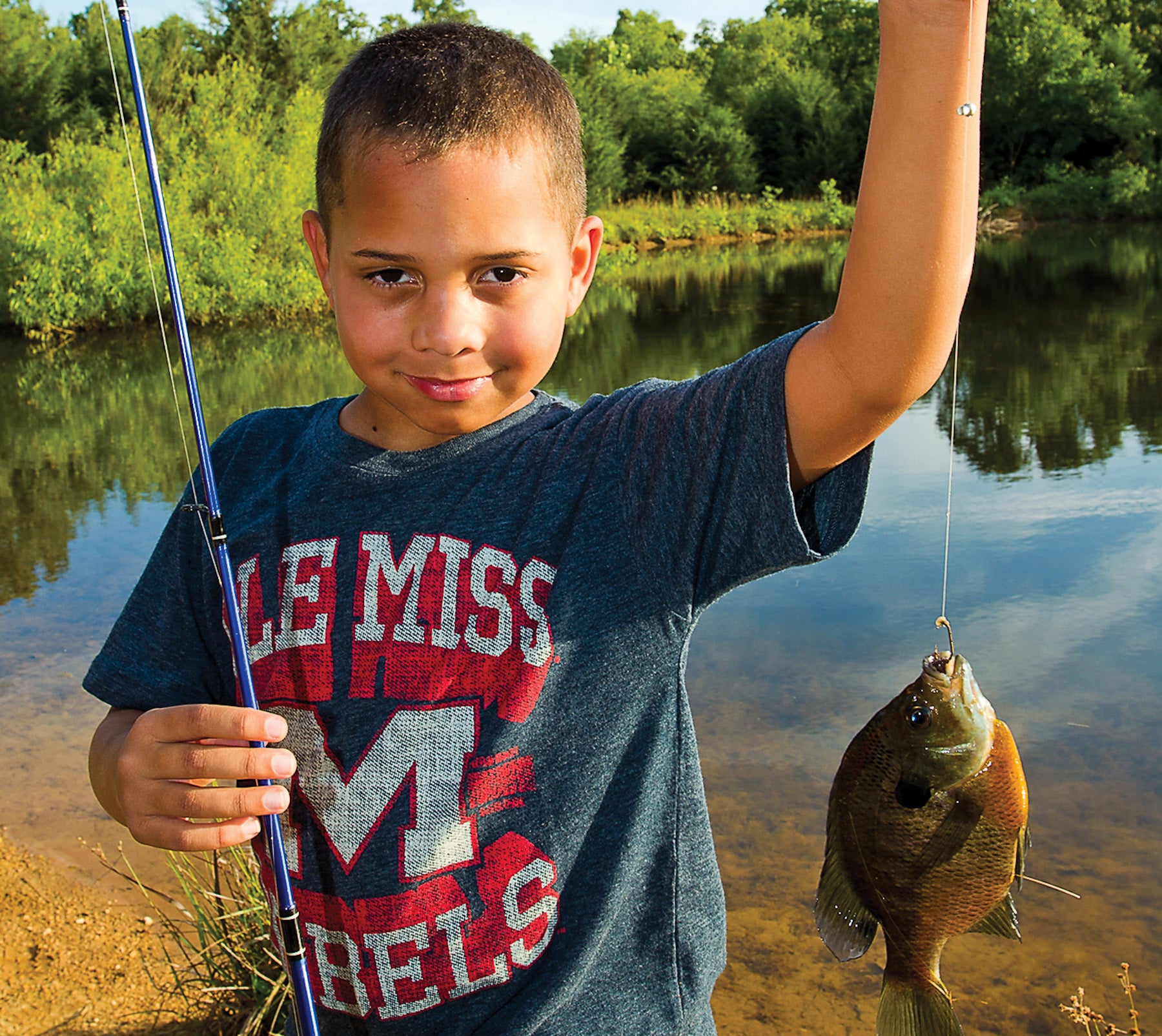 A young boy with a bluegill he has caught.