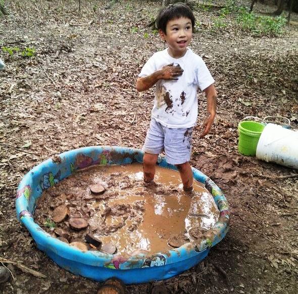 boy playing in pool of mud