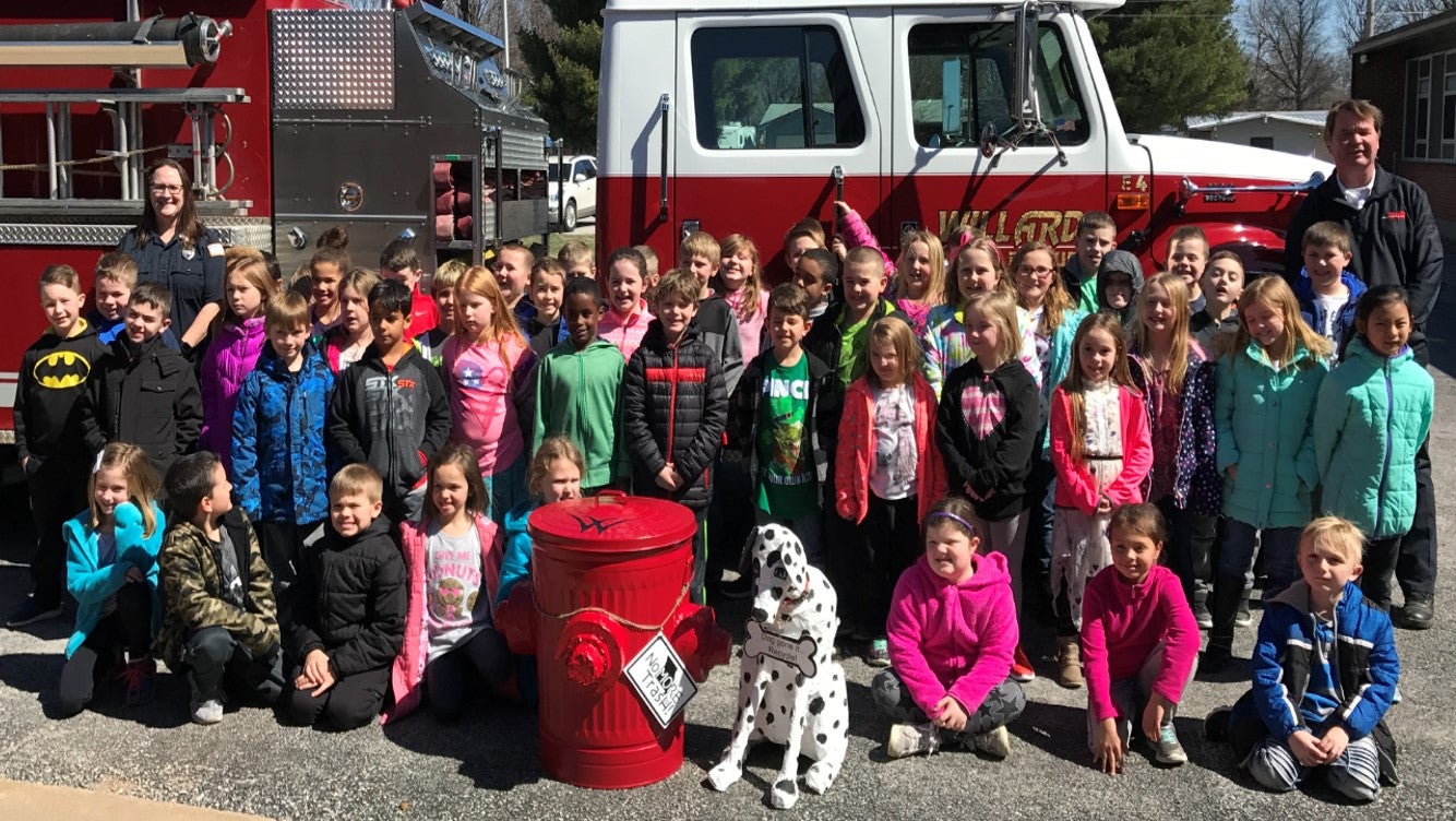 Students and fireman pose with winning trash can