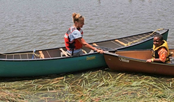 MDC staff person in canoe instructs kid in another canoe