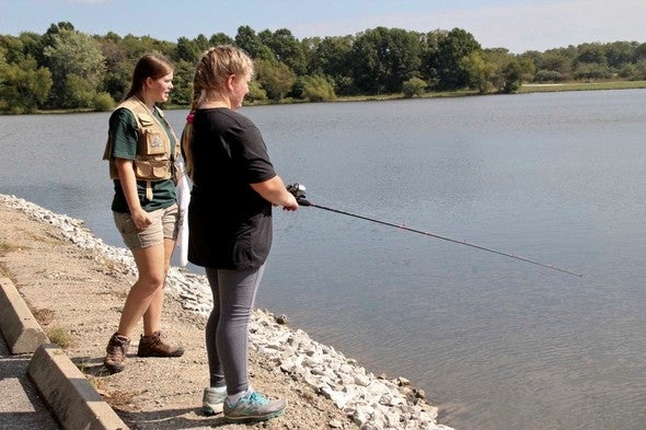 MDC staff person instructs woman fishing off bank