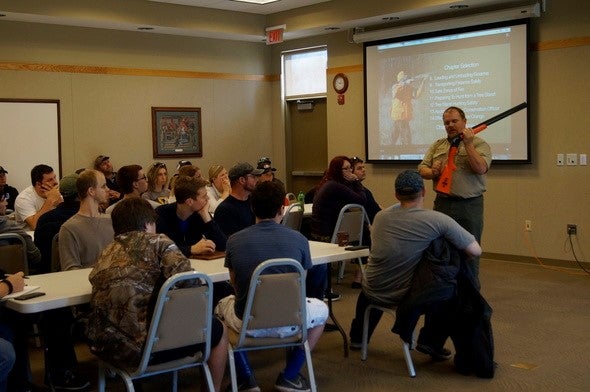 Instructor show how to handle a shotgun at a hunter education class.