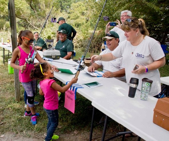 Children picking up fishing rods from a table at Family Outdoors Day