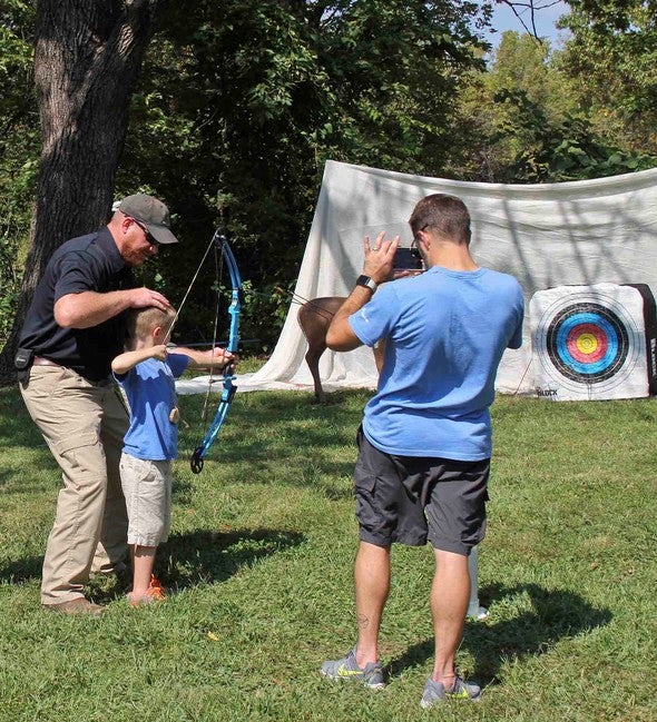 Little kid shooting a bow.