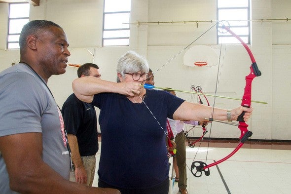 Man helps woman shoot bow