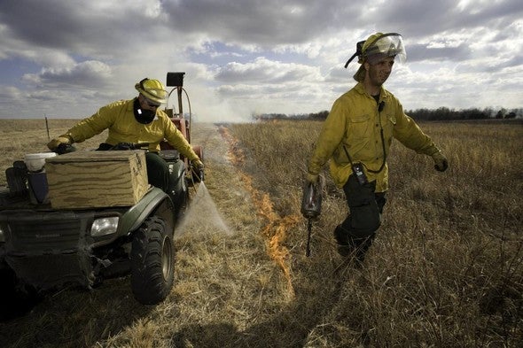Two technicians manage a prescribed burn.